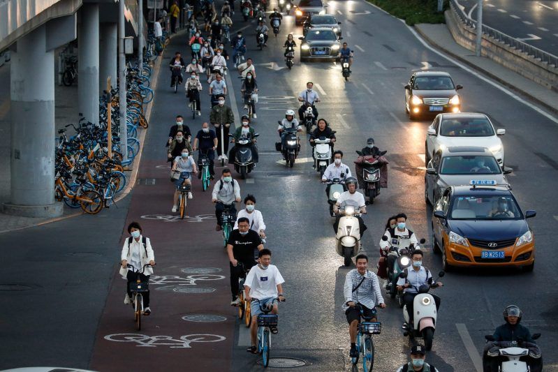 Personas circulan en bicicleta junto al tráfico en el distrito central de negocios de Beijing, China. Foto de EFE/ EPA/ MARK R. CRISTINO.